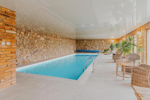 a swimming pool in a room with a stone wall at Natura vendégház in Abaújvár