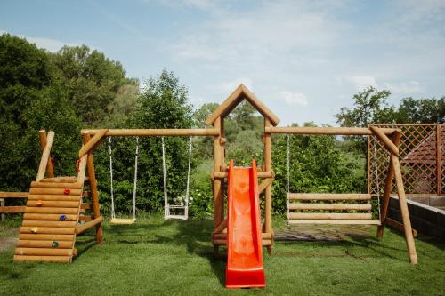 a playground with an orange slide and a swing at Natura vendégház in Abaújvár