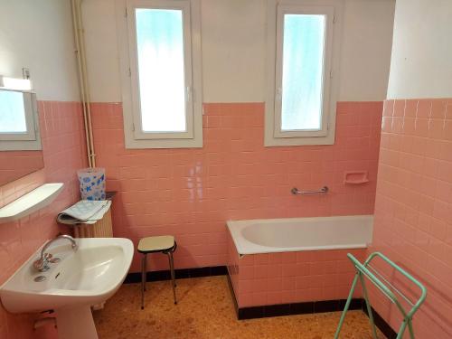 La salle de bains rose est pourvue d'un lavabo et d'une baignoire. dans l'établissement 120m2 rdc 2km mer soleil catalan 2ch wifi 4pers ok chéques vacances animaux, à Latour-Bas-Elne