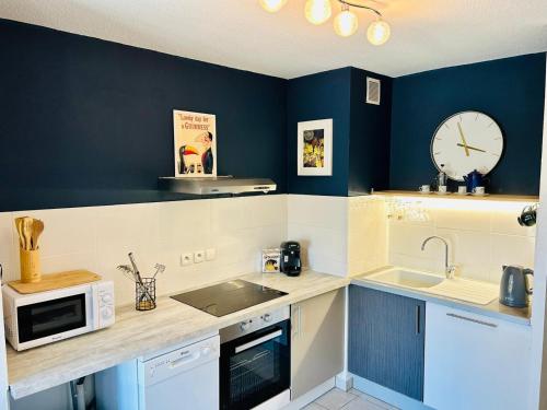 une cuisine avec un évier et une horloge murale dans l'établissement Nautilus Joli T3 Appartement Terrasse Climatisation, à Sète
