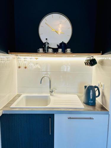 une cuisine avec un évier et une horloge murale dans l'établissement Nautilus Joli T3 Appartement Terrasse Climatisation, à Sète