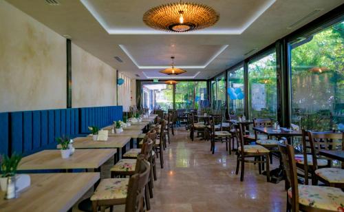 ein Restaurant mit Holztischen und -stühlen und Fenstern in der Unterkunft Hotel Corsa in Mangalia