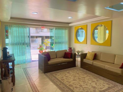 a living room with two couches and two mirrors at Bombinhas Praia Apart Hotel - unidade rua Bem Te Vi in Bombinhas