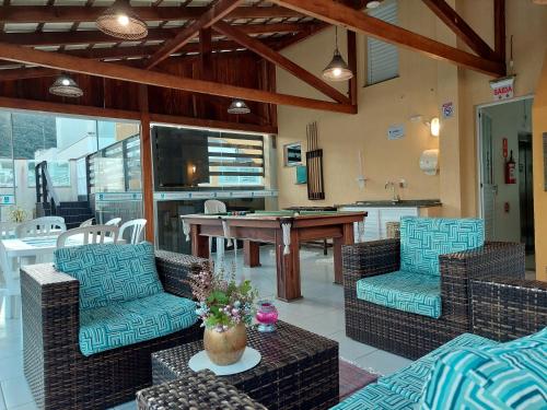 a living room with chairs and a table and a kitchen at Bombinhas Praia Apart Hotel - unidade rua Bem Te Vi in Bombinhas