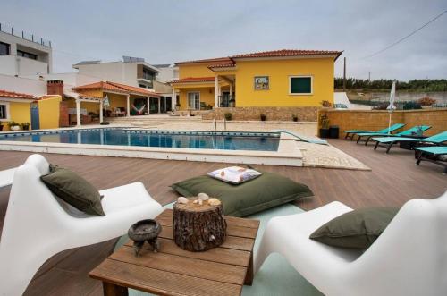 a patio with white chairs and a pool at Porto Dinheiro Beach II in Casal do Cigano