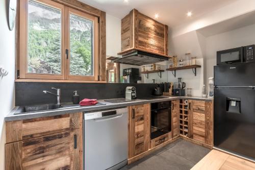 une cuisine avec des armoires en bois et un réfrigérateur noir dans l'établissement Le Chardonnet, à Sallanches