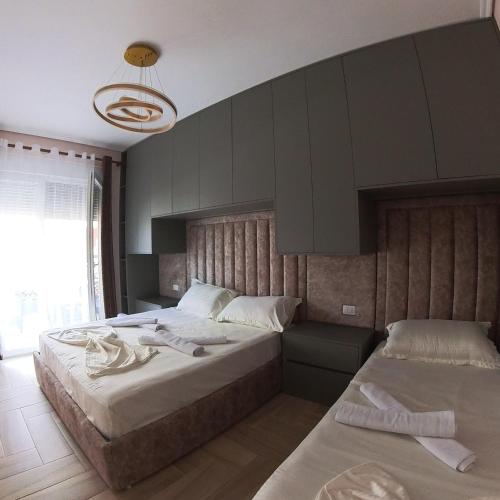 a bedroom with two beds and a hanging light at Sun Holiday Apartment in Lezhë