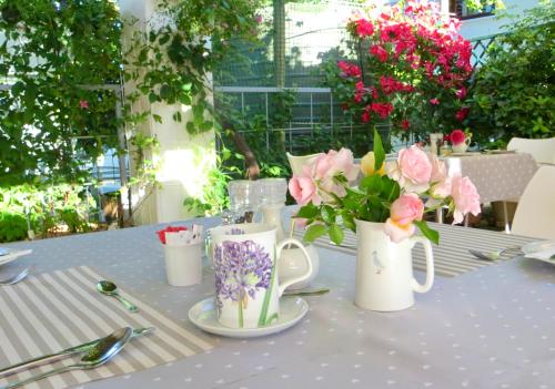 a table with two white vases with flowers on it at Penelope's Stellenbosch in Stellenbosch