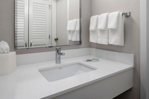a white bathroom with a sink and a mirror at Courtyard by Marriott Little Rock West in Little Rock