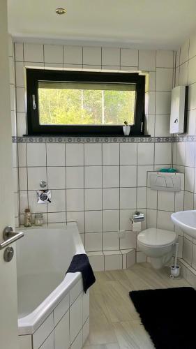 a bathroom with a tub and a toilet and a window at Ferienwohnung an der Wildenburg in Kempfeld