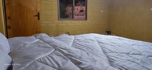 an unmade bed with white sheets in a bedroom at Dana historic village in Dana