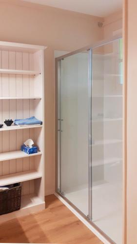 une douche dans une salle de bain avec une porte vitrée dans l'établissement Le Quai de Juillet, à Caen