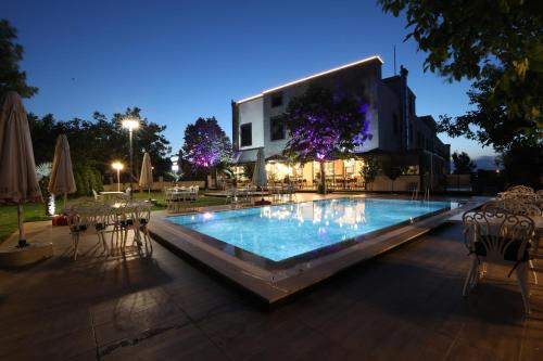 a swimming pool with tables and chairs in front of a building at İncipark Hotel in Sakarya