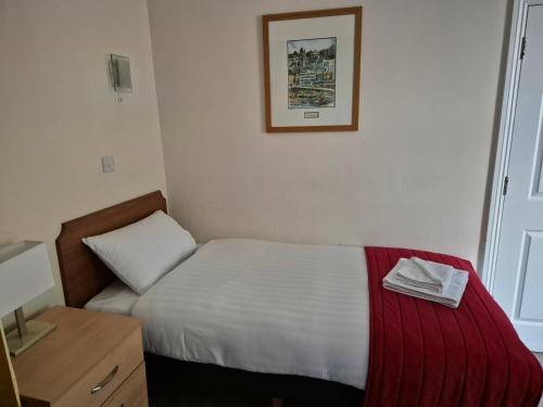 a small bedroom with a bed with a red blanket at Trecarn Hotel in Torquay