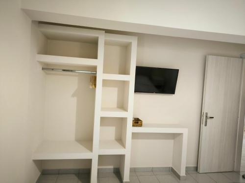 a room with white shelves and a tv on a wall at Aggelika Apartments in Lithakia