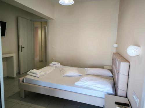 a bed with white sheets and pillows in a room at Aggelika Apartments in Lithakia