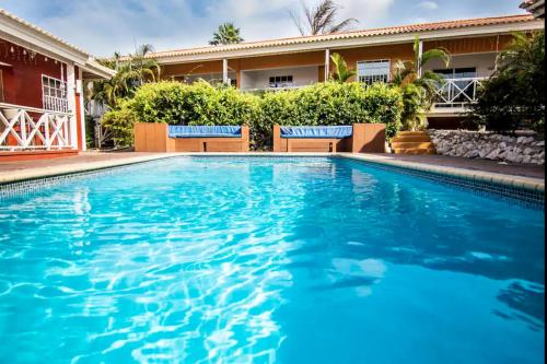 a swimming pool with blue water in front of a building at Beach Life Apartments in Jan Thiel