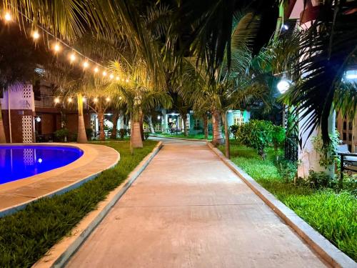 a pathway with palm trees and a pool at night at OAK Homes Diani in Diani Beach