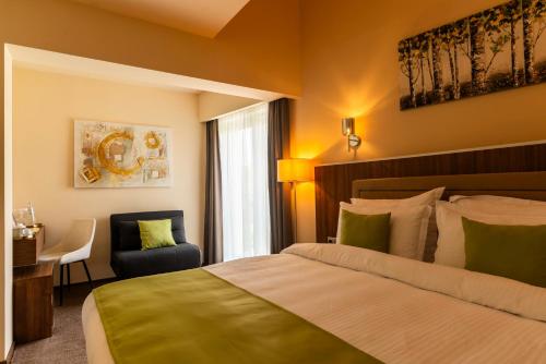 a hotel room with a bed and a chair at PENSIUNEA GAMBRINUS **** in Miercurea-Ciuc