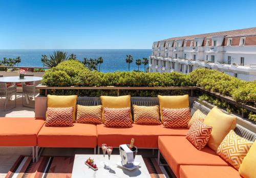 a couch on a balcony with the ocean in the background at Hôtel Barrière Le Gray d'Albion in Cannes