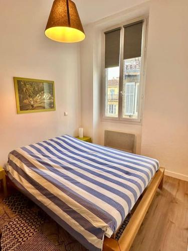 une chambre avec un lit avec une couverture rayée bleue et blanche dans l'établissement Joli T2 avec cachet La plaine Cours Julien, à Marseille