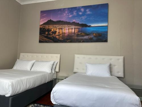 a bedroom with two beds and a painting on the wall at Prime Executive Accommodation in Cape Town