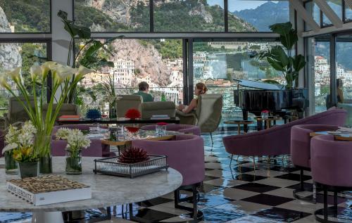 a hotel lobby with purple chairs and a piano at Hotel Miramalfi in Amalfi