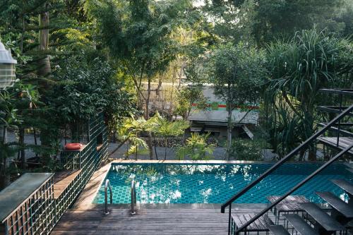 a swimming pool in a garden with a wooden deck at Sometimes Khaoyai in Ban Muak Lek Nai