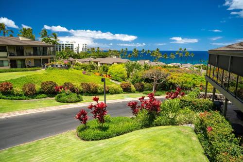 a street in front of a resort with flowers and the ocean at Elua 406 in Wailea