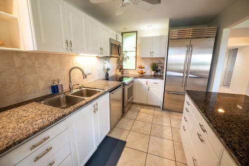 a kitchen with white cabinets and a stainless steel refrigerator at Elua 406 in Wailea