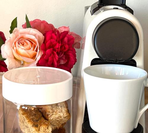 a container of food next to a toaster and flowers at Penelope's Stellenbosch in Stellenbosch