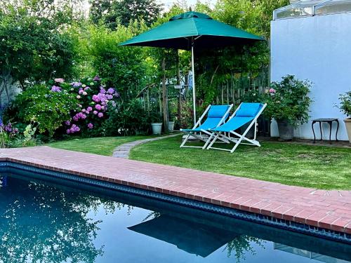 two blue chairs and an umbrella next to a pool at Penelope's Stellenbosch in Stellenbosch