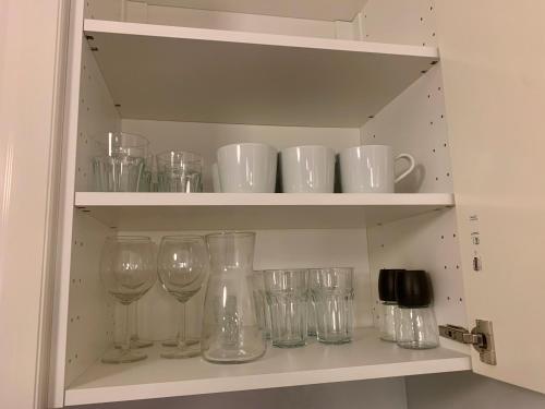 a shelf with wine glasses and cups on it at Apartament Teatralny - Komfort w Sercu Miasta Klimatyzacja in Opole