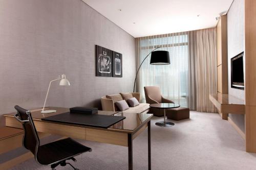 a living room with a couch and a desk in a room at Le Meridien Taipei in Taipei