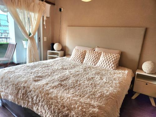 ein Schlafzimmer mit einem Bett mit weißer Bettdecke und einem Fenster in der Unterkunft Petit Lacroze in Buenos Aires