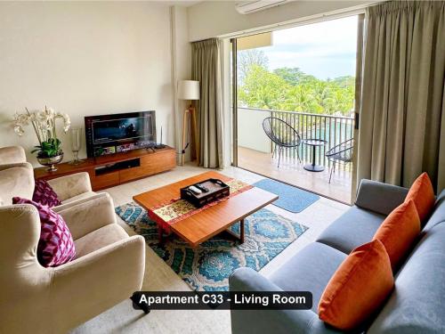 a living room with a couch and a tv at By the Sea- Pool and Sea View in Batu Ferringhi