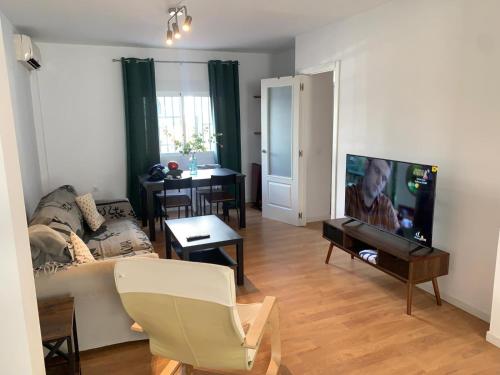 salon z kanapą i telewizorem z płaskim ekranem w obiekcie Casa Amapola - Costa Bahía de Cádiz w mieście Puerto Real