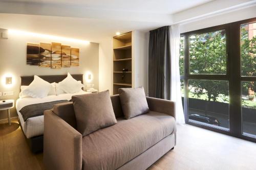 a bedroom with a bed and a couch and a window at Sercotel Valencia Alameda 41 in Valencia