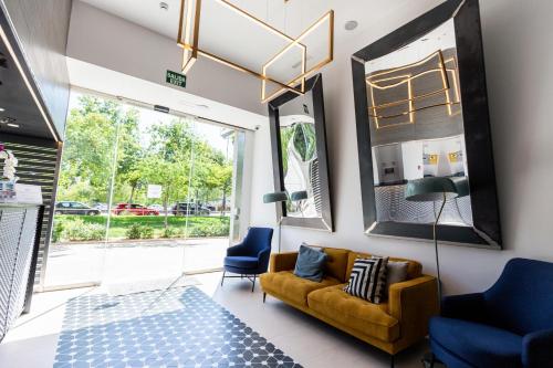 a living room with a yellow couch and blue chairs at Sercotel Valencia Alameda 41 in Valencia