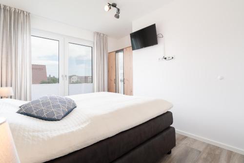 a white bedroom with a large bed and a window at Steife Brise Nr 2 in Neustadt in Holstein