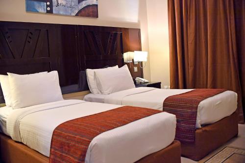 a hotel room with two beds and a telephone at Emirates Stars Hotel Apartments Sharjah in Sharjah
