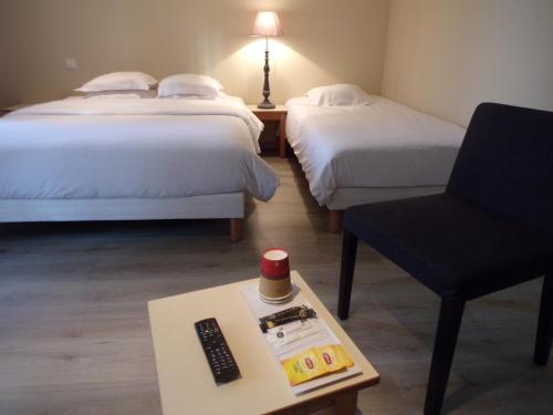 a hotel room with two beds and a chair and a remote control at Domaine de Bel Air in Cérans-Foulletourte