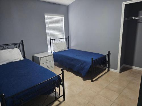 a bedroom with two beds with blue sheets and a window at Mufasa's Pride in Kissimmee