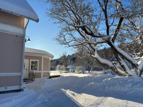 a house covered in snow next to a tree at Rosa Huset Osebol in Stöllet