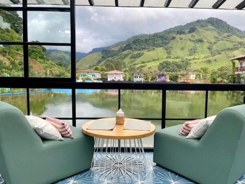 a room with two chairs and a table and a large window at Hotel Lago Valdivia in Jardin