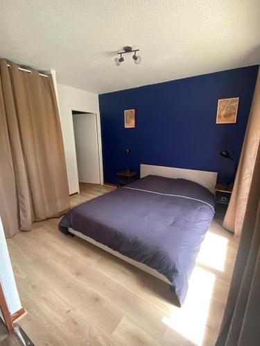 a bedroom with a bed with a blue wall at Roy apartment in Douvaine