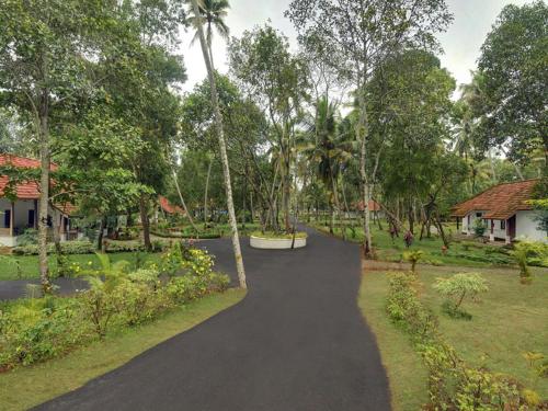 a path through a park with trees and a house at Abad Turtle Beach in Mararikulam