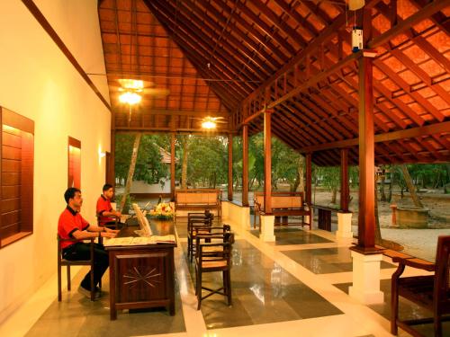 two men sitting at a table in a pavilion at Abad Turtle Beach in Mararikulam