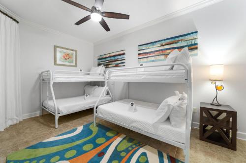 a bedroom with two bunk beds and a ceiling fan at The Oasis At Orange Beach 2215 by Liquid Life in Orange Beach