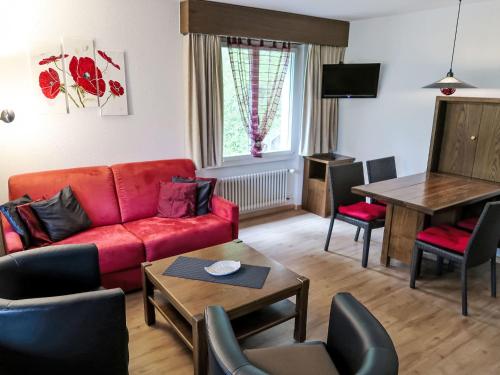 a living room with a red couch and a table at Apartment Ringstrasse - Utoring-38 by Interhome in Leukerbad